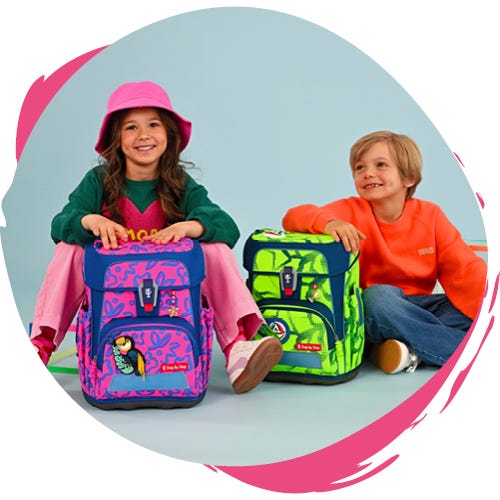 Zwei Kinder sitzen mit neonfarbenen Schulranzen auf dem Boden