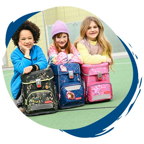 Kinder sitzen mit ihren bunten Schulranzen auf dem Pausenhof