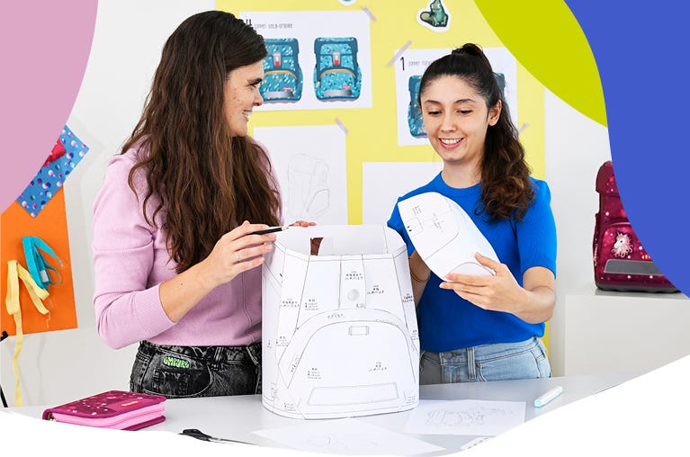 Zwei Personen arbeiten mit Papierprototyp und Entwurfsskizzen an der Entwicklung eines Schulranzens.