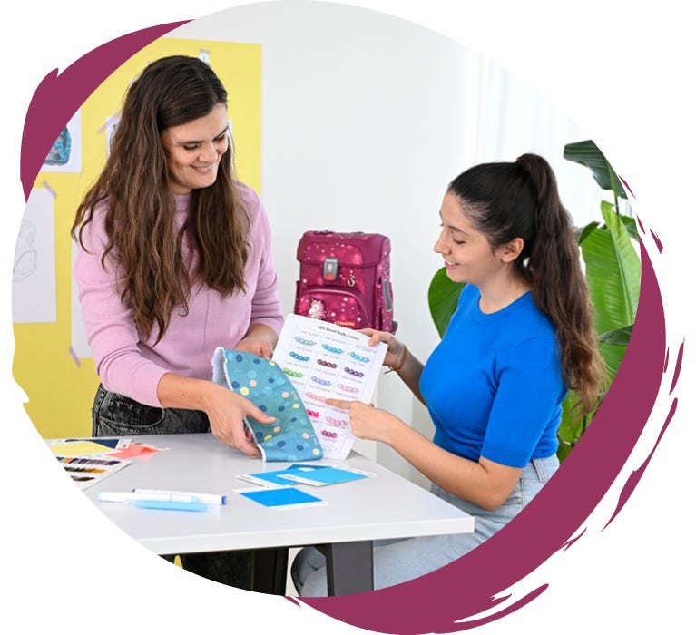 Zwei Personen w&auml;hlen gemeinsam Motive, Farben und Materialien f&uuml;r die Gestaltung eines Schulranzens aus.
