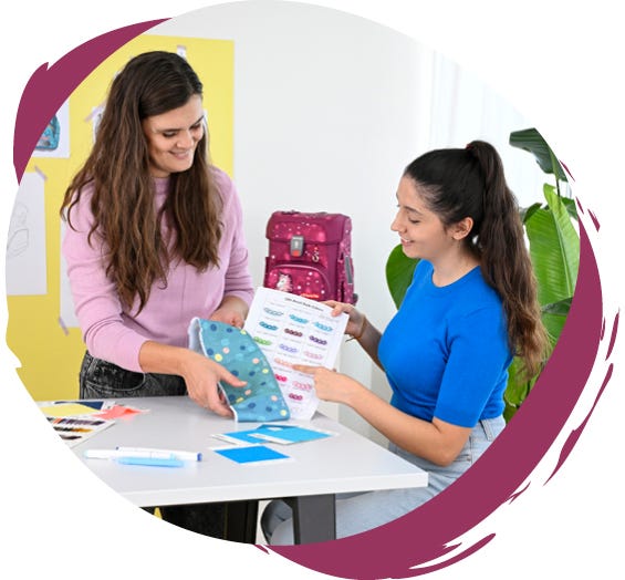 Zwei Personen w&auml;hlen gemeinsam Motive, Farben und Materialien f&uuml;r die Gestaltung eines Schulranzens aus.