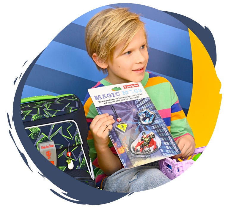 Ein Kind zeigt verschiedene kindgerechte Designs, die am Schulranzen ausgetauscht werden können.