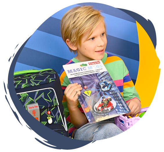 Ein Kind zeigt verschiedene kindgerechte Designs, die am Schulranzen ausgetauscht werden können.