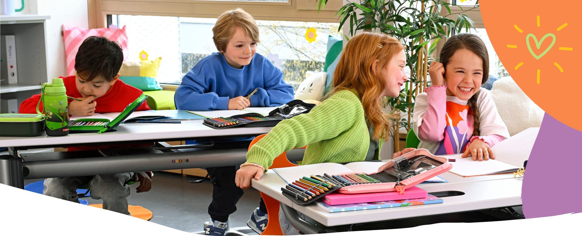 Kinder arbeiten im Klassenzimmer mit Federm&auml;ppchen, Stiften und Heften an ihren Schreibtischen in einer hellen Lernumgebung.