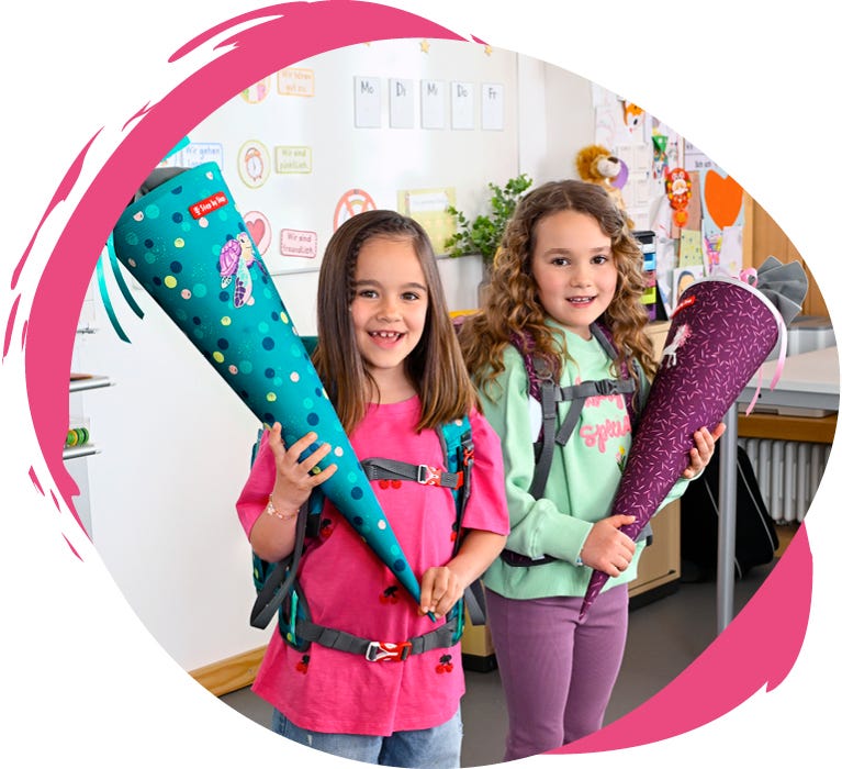 Zwei Kinder mit Schulrucks&auml;cken und passenden Schult&uuml;ten im Klassenzimmer.