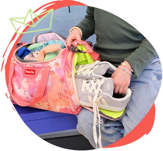 Rosafarbene Sporttasche mit Herzmuster wird mit Turnschuhen und Sportausr&uuml;stung gepackt.