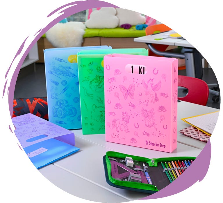 Farbige Schulmappen und Schnellhefter mit Feen-, Einhorn- und Fahrzeugmotiven auf einem Tisch im Klassenzimmer.