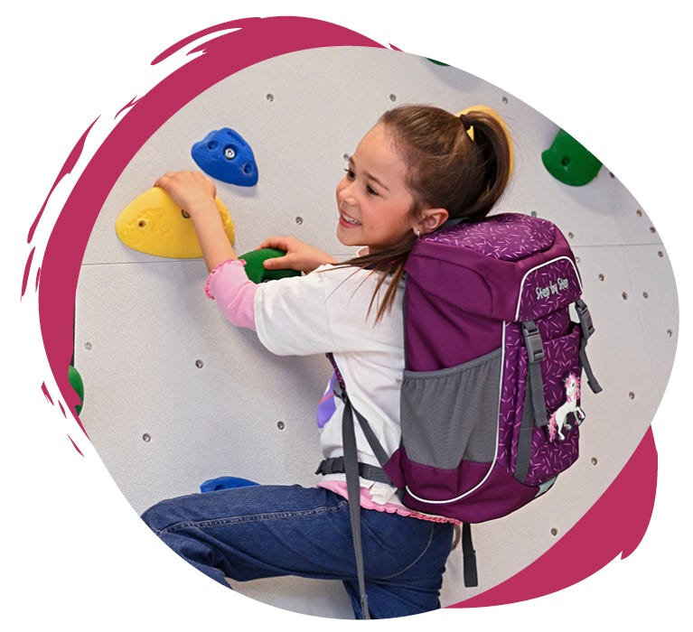 ACTIVE Kind klettert mit violettem Rucksack mit Einhornmotiv an einer Kletterwand mit bunten Griffen.