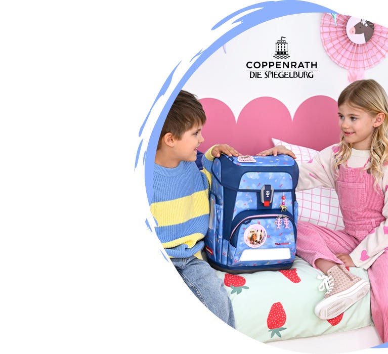 Zwei Kinder pr&auml;sentieren einen hellblauen Schulranzen der Spiegelburg-Kollektion auf einem Bett. Logo: &sbquo;Coppenrath Die Spiegelburg&lsquo;.