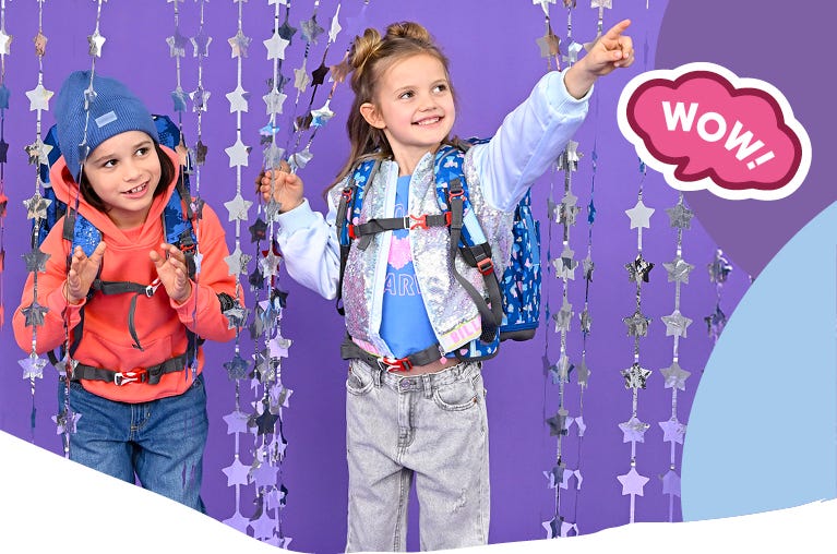 Zwei Kinder mit blauen Schulrucks&auml;cken vor violettem Hintergrund mit Sternengirlanden. Text: &sbquo;WOW!&lsquo;.