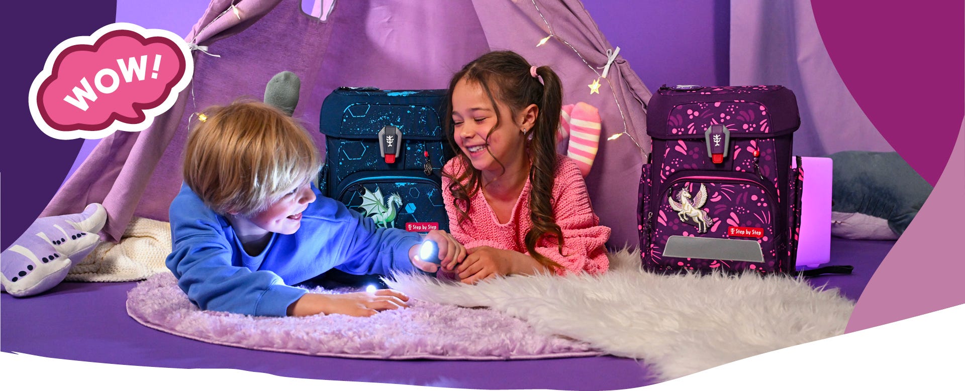 Zwei Kinder mit Taschenlampe vor einem Stoffzelt, daneben Schulranzen mit Drachen- und Einhornmotiv. Text: &sbquo;WOW!&lsquo;