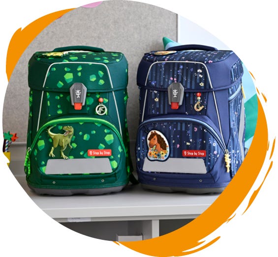 Zwei Schulranzen auf einem Tisch: links ein gr&uuml;ner mit Dinosaurier-Motiv, rechts ein blauer mit Pferde-Design.