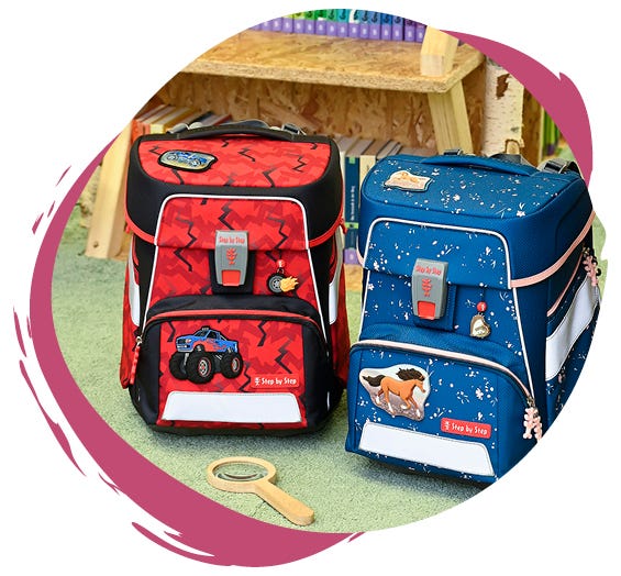 Zwei Schulranzen auf einem Teppichboden: links ein roter mit Monstertruck-Motiv, rechts ein blauer mit Pferde-Design.