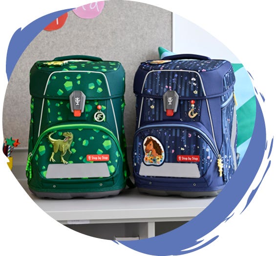 Mädchen Schulranzen in verschiedenen Designs Zwei Schulthek auf einem Tisch: links ein grüner mit Dinosaurier-Motiv, rechts ein blauer mit Pferde-Design.
