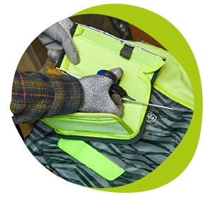 Mit Schutzhandschuhen wird ein M&auml;ppchen zur Materialtrennung und Wiederverwertung mit einer Schere zerlegt.
