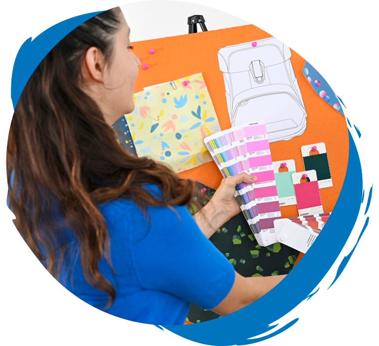 Person w&auml;hlt Farben und Materialien f&uuml;r das Design eines Schulranzens anhand einer Farbkarte und einer Design-Pinnwand aus.