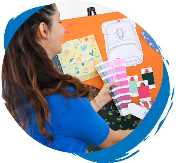 Person w&auml;hlt Farben und Materialien f&uuml;r das Design eines Schulranzens anhand einer Farbkarte und einer Design-Pinnwand aus.