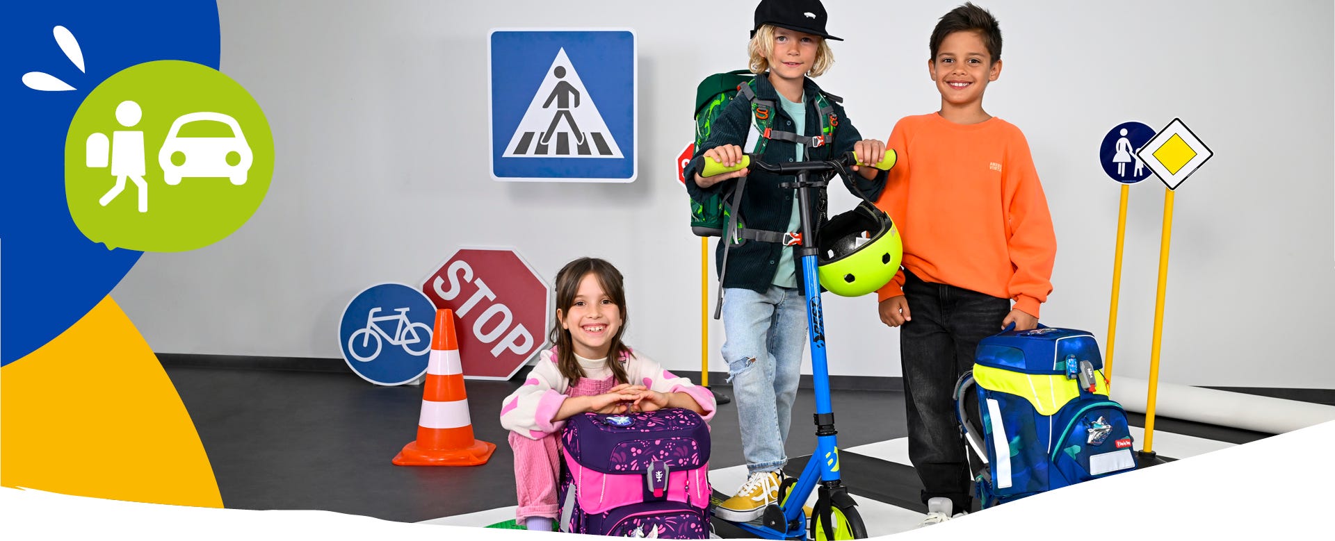Kinder mit Schulranzen in einer Lernumgebung zur Verkehrssicherheit mit Verkehrsschildern, Roller und reflektierenden Schulranzen.